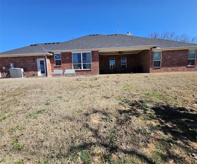 back of house with a shingled roof, brick siding, and central air condition unit