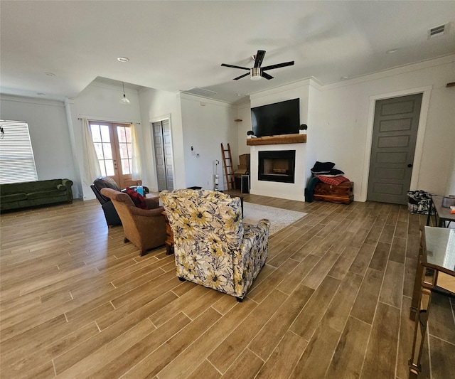 living room with ornamental molding, french doors, a fireplace, and wood finished floors