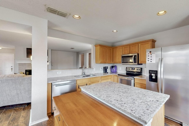 kitchen featuring visible vents, a sink, a kitchen island, dark wood-style floors, and appliances with stainless steel finishes