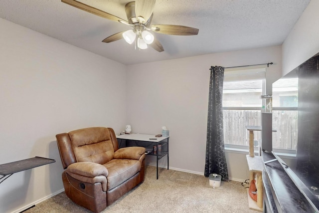 living area featuring a textured ceiling, carpet flooring, a ceiling fan, and baseboards