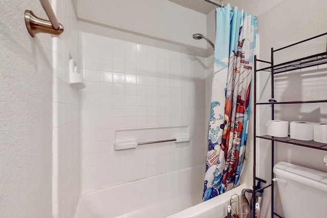 bathroom featuring a textured wall, toilet, and shower / bathtub combination with curtain