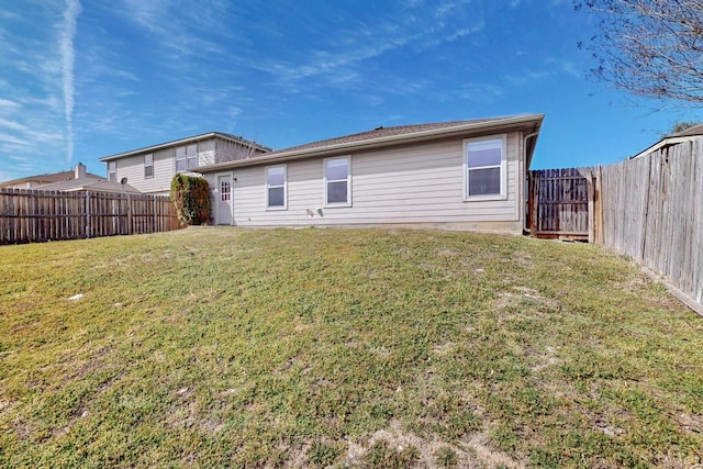 rear view of property featuring a lawn and a fenced backyard