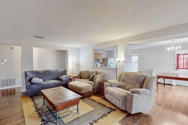 living room with visible vents, a notable chandelier, wood finished floors, and a textured ceiling