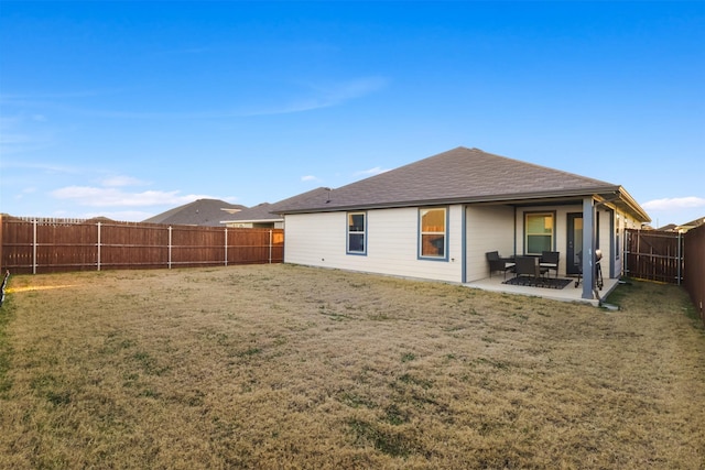 back of house with a yard, roof with shingles, a patio area, and a fenced backyard