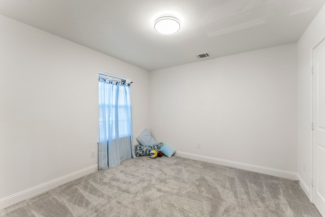 carpeted spare room with visible vents and baseboards