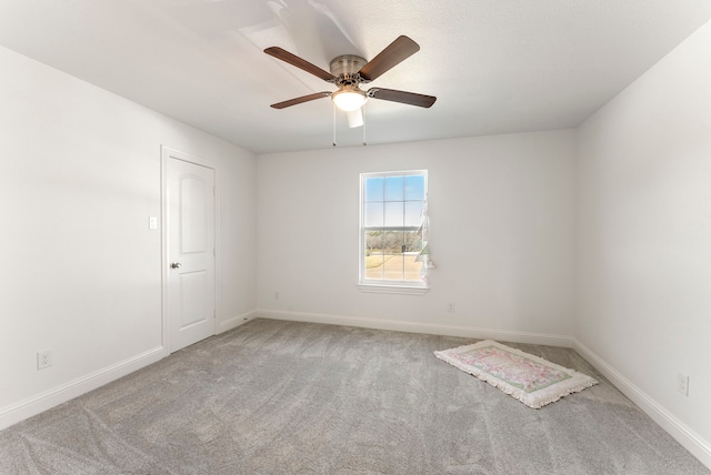 carpeted empty room with baseboards and a ceiling fan