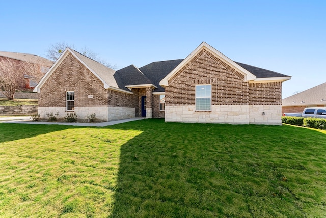 ranch-style home featuring a shingled roof, a front yard, and brick siding