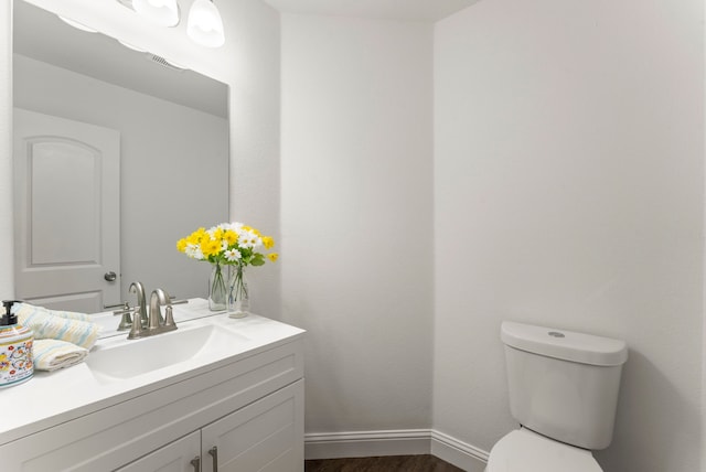 bathroom featuring wood finished floors, vanity, toilet, and baseboards