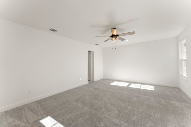 empty room with a ceiling fan, carpet, visible vents, and baseboards