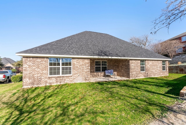 rear view of house featuring a patio area, a shingled roof, brick siding, and a yard