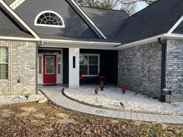 property entrance featuring covered porch and brick siding