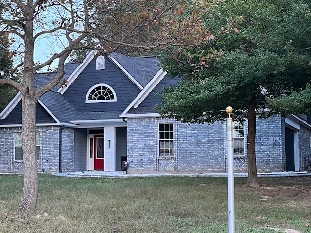 view of front facade with a front yard and brick siding