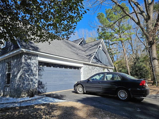 view of side of home with brick siding, an attached garage, a shingled roof, and aphalt driveway