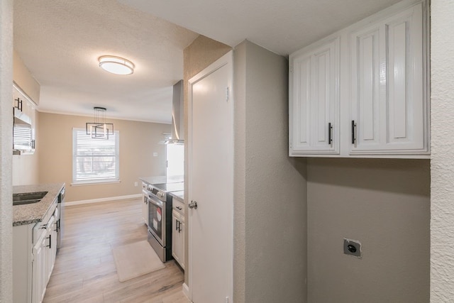 kitchen with a sink, white cabinetry, baseboards, appliances with stainless steel finishes, and light wood-type flooring