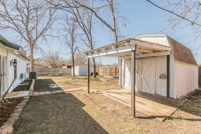 view of yard featuring central air condition unit, a fenced backyard, an outdoor structure, and a shed