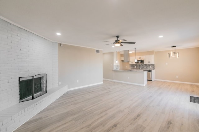 unfurnished living room with light wood-style flooring, a fireplace, visible vents, and baseboards