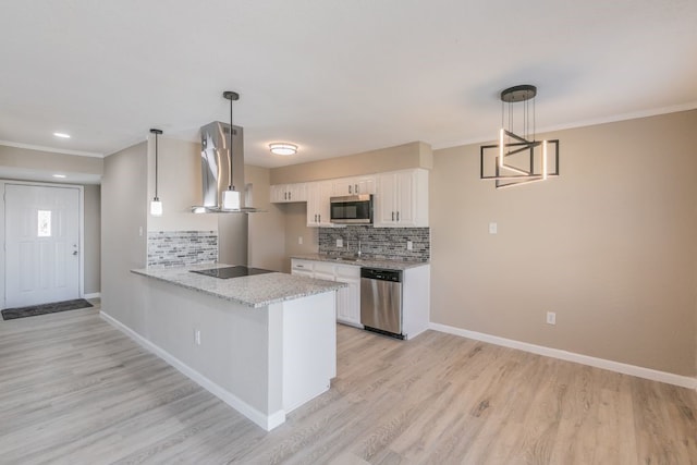 kitchen with a peninsula, white cabinetry, baseboards, appliances with stainless steel finishes, and wall chimney range hood