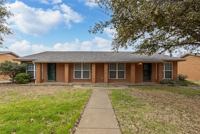 ranch-style home with a shingled roof, a front yard, and brick siding