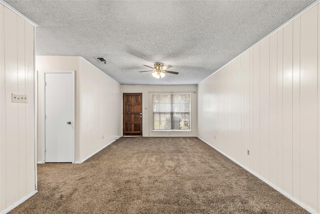 empty room featuring carpet floors, visible vents, ceiling fan, and a textured ceiling