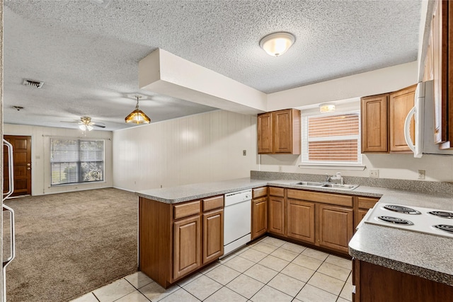 kitchen featuring white appliances, visible vents, light colored carpet, a peninsula, and a sink