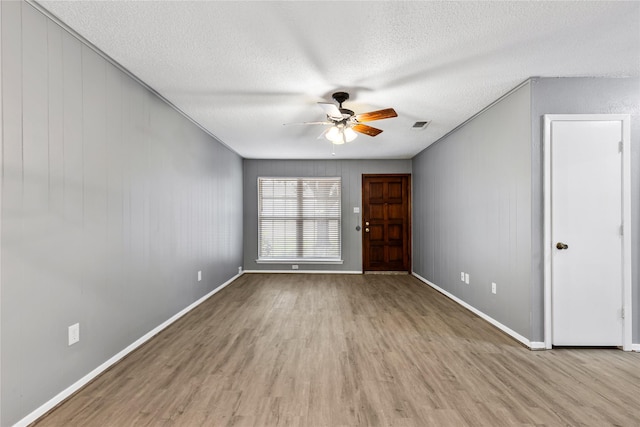 spare room with visible vents, ceiling fan, a textured ceiling, wood finished floors, and baseboards