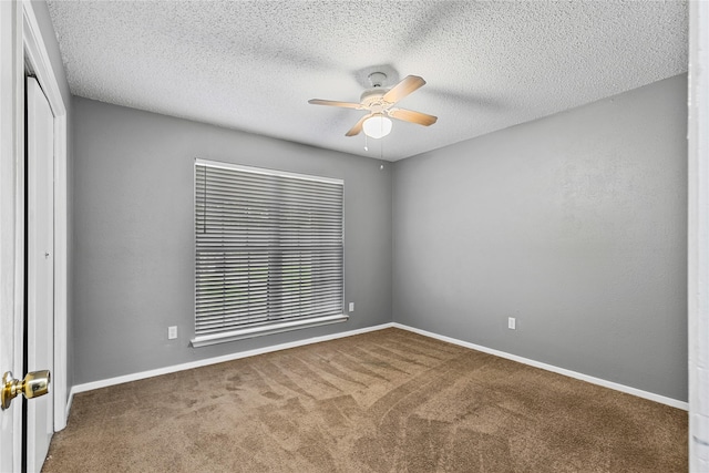 carpeted spare room with a textured ceiling, a ceiling fan, and baseboards