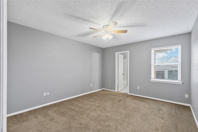 spare room featuring a ceiling fan, carpet, a textured ceiling, and baseboards