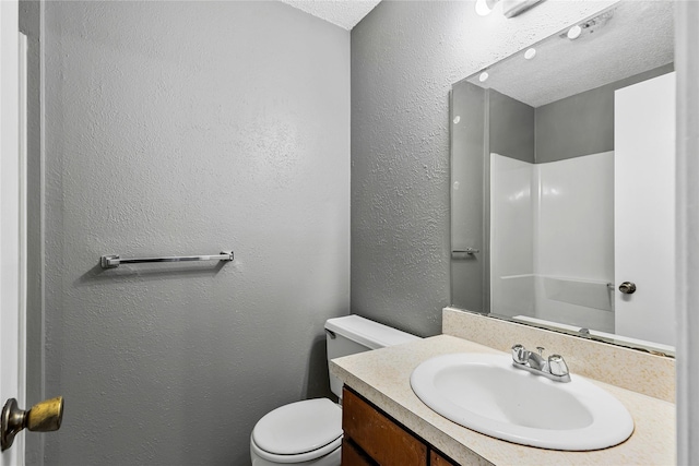 full bathroom featuring a textured ceiling, a textured wall, vanity, and toilet