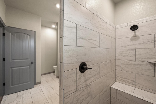 full bathroom featuring marble finish floor, tiled shower, baseboards, and toilet