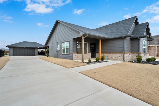 view of front of house featuring a garage, an outbuilding, brick siding, and a shingled roof