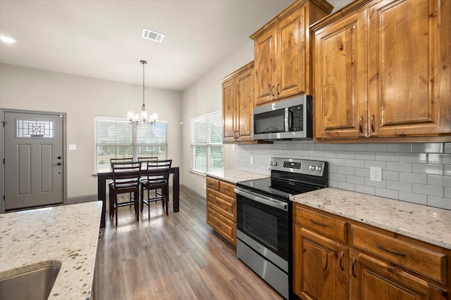 kitchen with stainless steel appliances, brown cabinetry, visible vents, and decorative backsplash