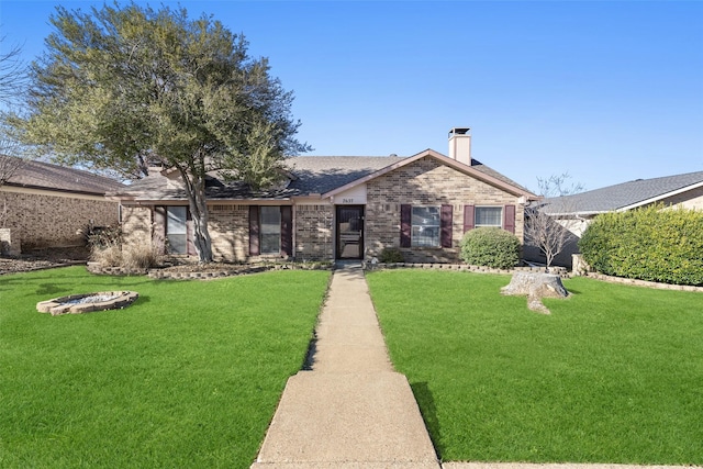 single story home featuring a front yard, a chimney, and brick siding