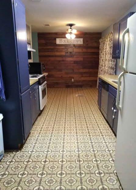 kitchen with dishwasher, freestanding refrigerator, range hood, blue cabinetry, and wood walls