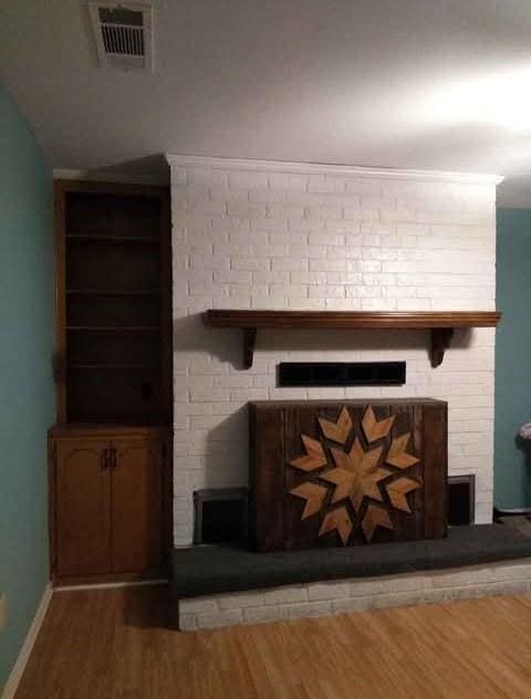 room details featuring visible vents, a fireplace, baseboards, and wood finished floors