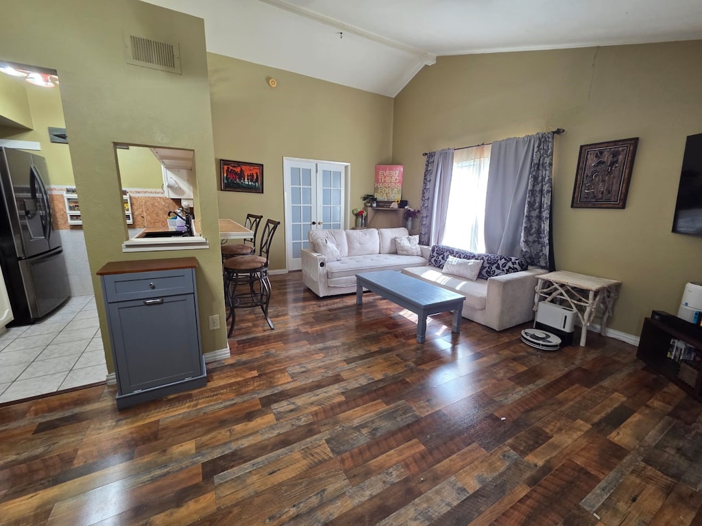 living area with french doors, visible vents, hardwood / wood-style floors, high vaulted ceiling, and baseboards