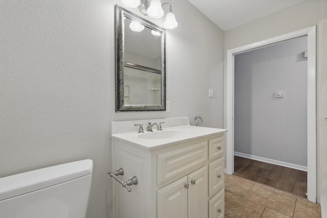 bathroom with toilet, baseboards, and vanity