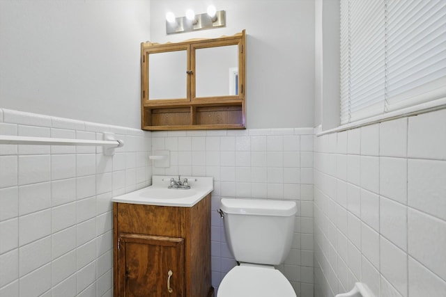 half bath featuring a wainscoted wall, vanity, and toilet