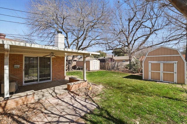 view of yard with ceiling fan, an outbuilding, a storage shed, fence, and a patio area