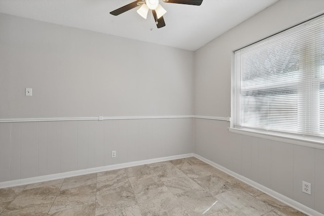 spare room with ceiling fan and wainscoting