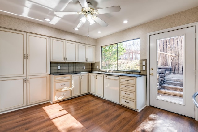 kitchen featuring dark countertops, dark wood-style flooring, dishwasher, and cream cabinets