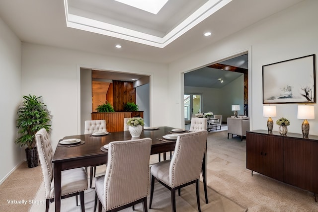 dining space featuring a skylight, light carpet, a tray ceiling, and recessed lighting