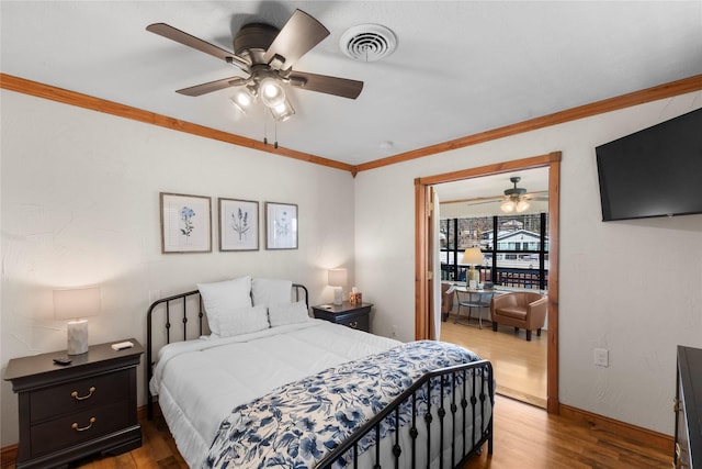 bedroom featuring ornamental molding, wood finished floors, visible vents, and baseboards