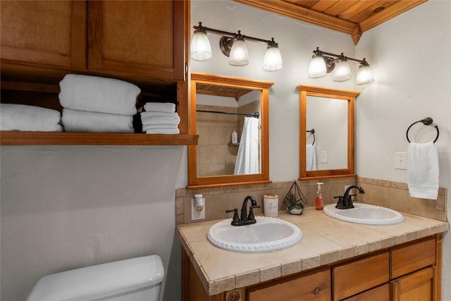 full bath with toilet, crown molding, double vanity, and a sink