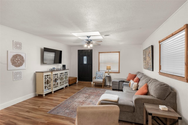 living area featuring baseboards, visible vents, ceiling fan, wood finished floors, and a textured ceiling