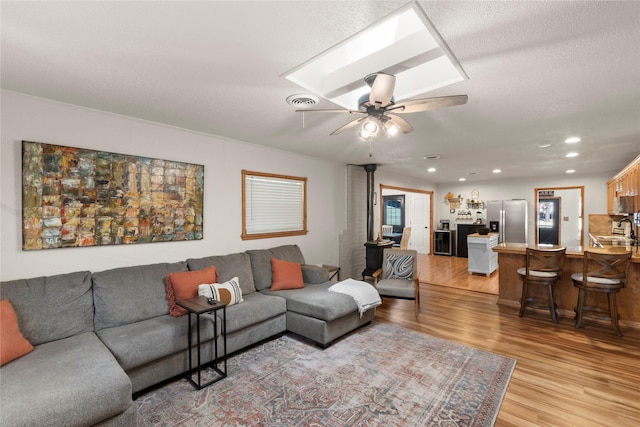 living area featuring light wood-style floors, recessed lighting, a textured ceiling, and a ceiling fan