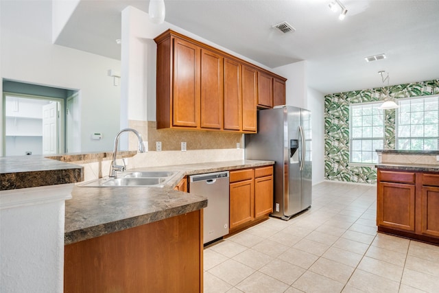 kitchen featuring brown cabinetry, visible vents, stainless steel appliances, and a sink