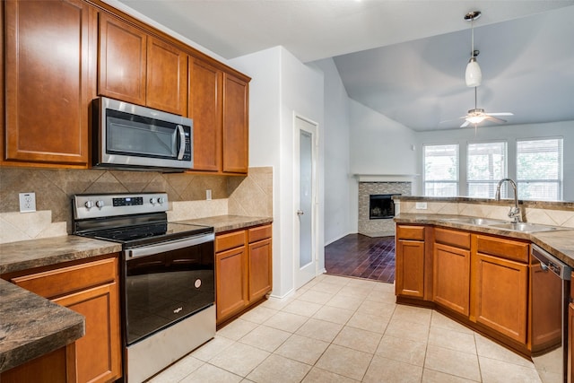 kitchen with light tile patterned floors, appliances with stainless steel finishes, brown cabinetry, and a sink