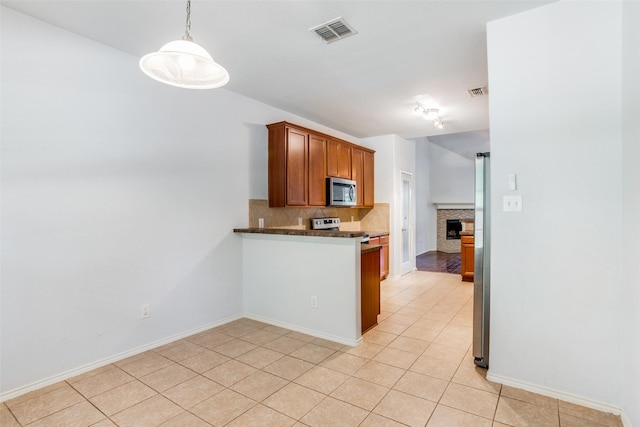 kitchen featuring a fireplace, light tile patterned floors, stainless steel appliances, tasteful backsplash, and visible vents