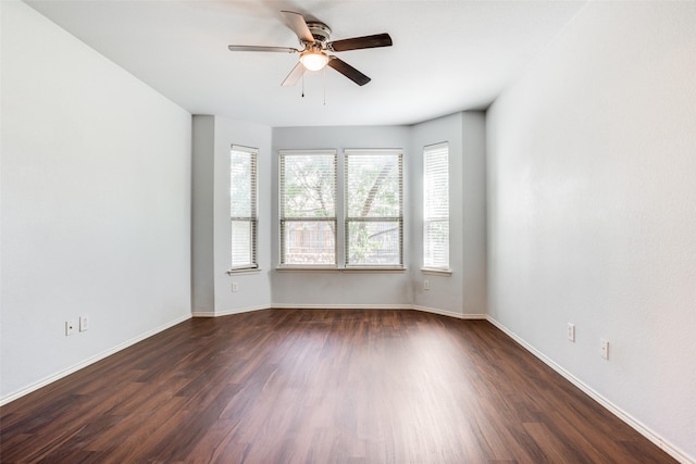 spare room with baseboards, dark wood finished floors, and a ceiling fan