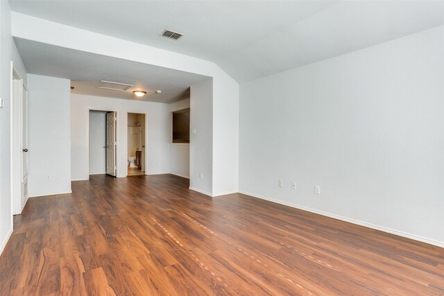 unfurnished room with attic access, baseboards, visible vents, lofted ceiling, and dark wood-style flooring